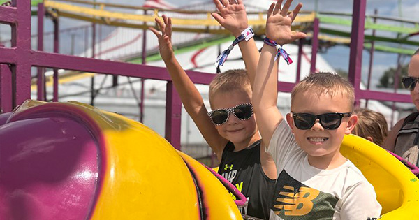Two smiling little boys on a carnival ride at the Fair