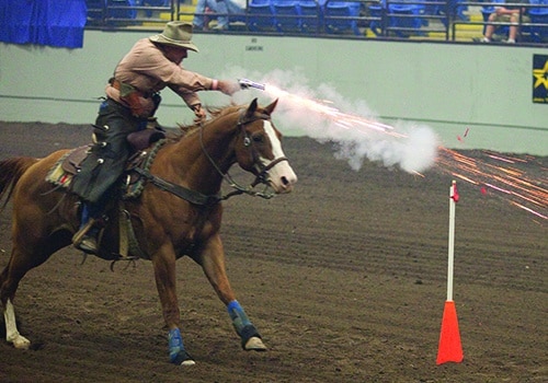 Cowboy Mounted Shooter on horse shooting at target during the Cowboy Mounted Shooting contest