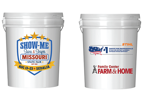Two white buckets with colorful graphics. The left bucket features a "Show-Me Missouri State Fair" design with stars. The right shows logos for Stihl and Family Center Farm & Home.