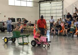 Little girl on pink tractor in the pedal pull