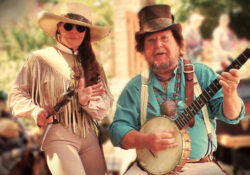 A man, Professor Farquare, in a top hat plays a banjo next to a woman, Polecat Annie, in fringed attire and a wide-brimmed hat, creating a lively and rustic outdoor setting.