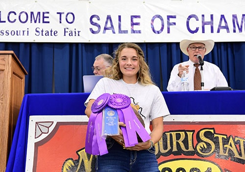 Exhibitor showcasing her Grand Champion Ham at Sale of Champions