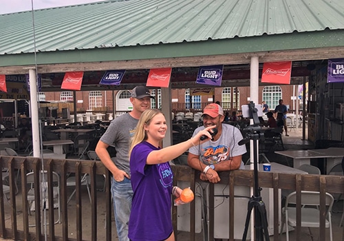 Woman and two men in front of tripod recording a video