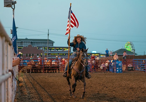 Woman carrying the American flag while riding horse