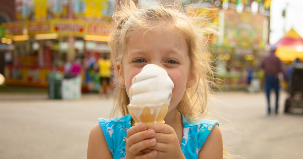 A happy little girl with a big vanilla ice cream cone at the Fair