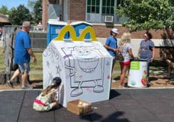 A girl coloring on a giant Happy Meal box