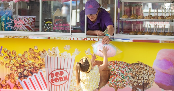 A concessionaire handing a young girl cotton candy