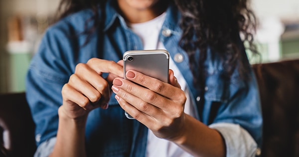 A woman holding a smartphone in the palm of her hand