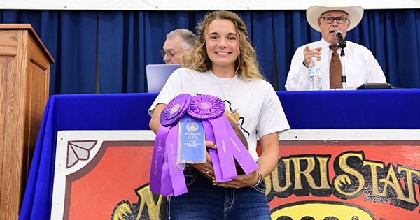 A girl holding several competition ribbons