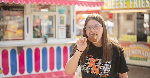 A girl eating a caramel apple at the Fair