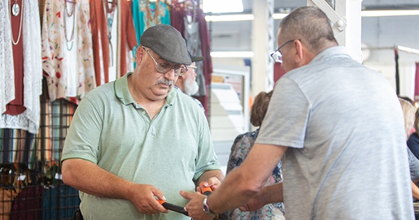 A vendor demonstration products to a customer at a fair booth