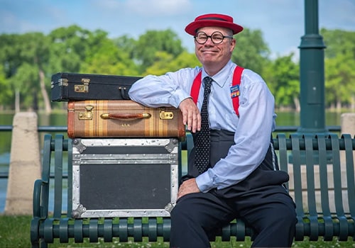 Kenny Ahern sitting on a bench with luggage