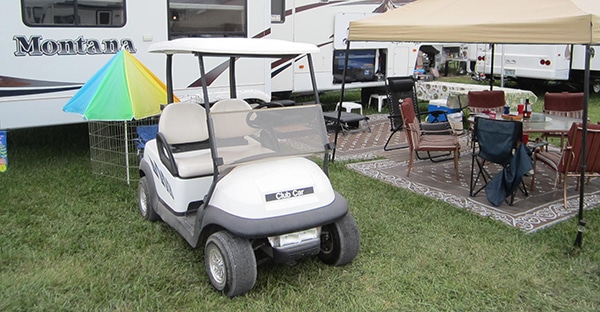 Public campsite with a camper, golf cart and canopy with chairs