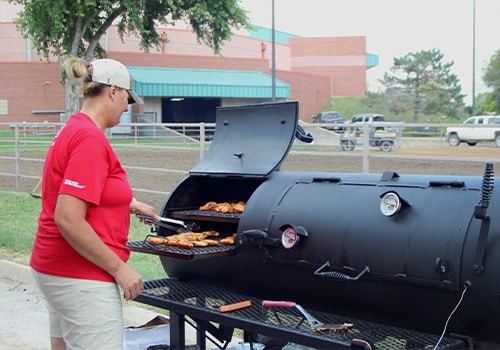 A woman cooking on a BBQ grill